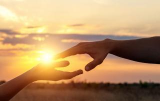 2 hands reaching to touch with sunset over landscape near hollywood CA