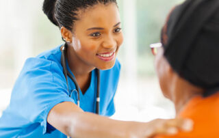 hospice care nurse caregiver smiling and placing hand on person in her care